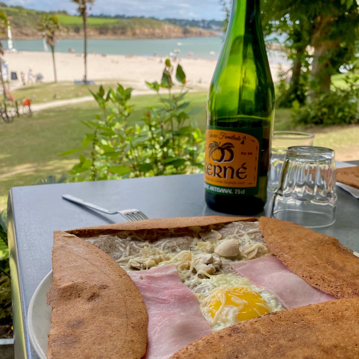 thin pancake with egg ham and cheese with bottle of cider at the beach