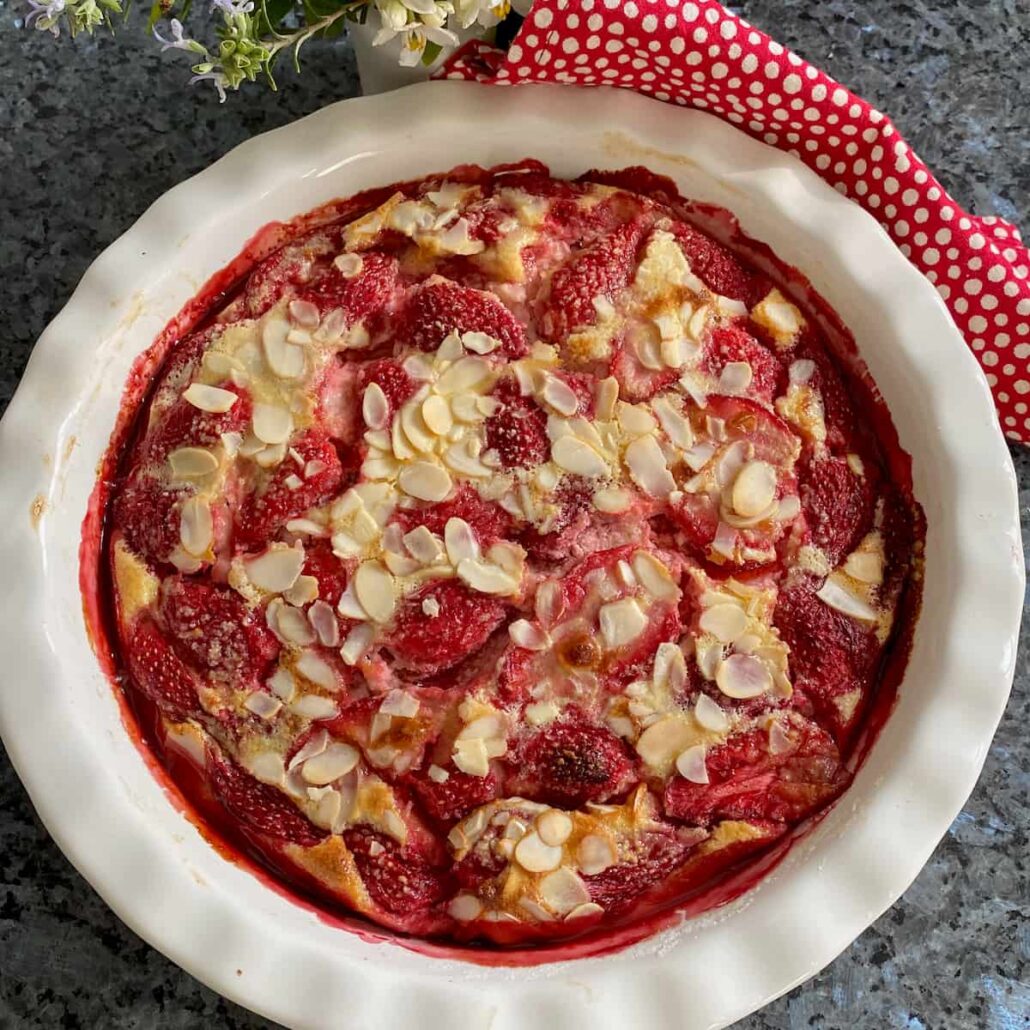 round pie dish with baked strawberries and almonds in a custard