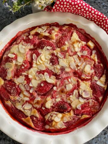 round pie dish with baked strawberries and almonds in a custard