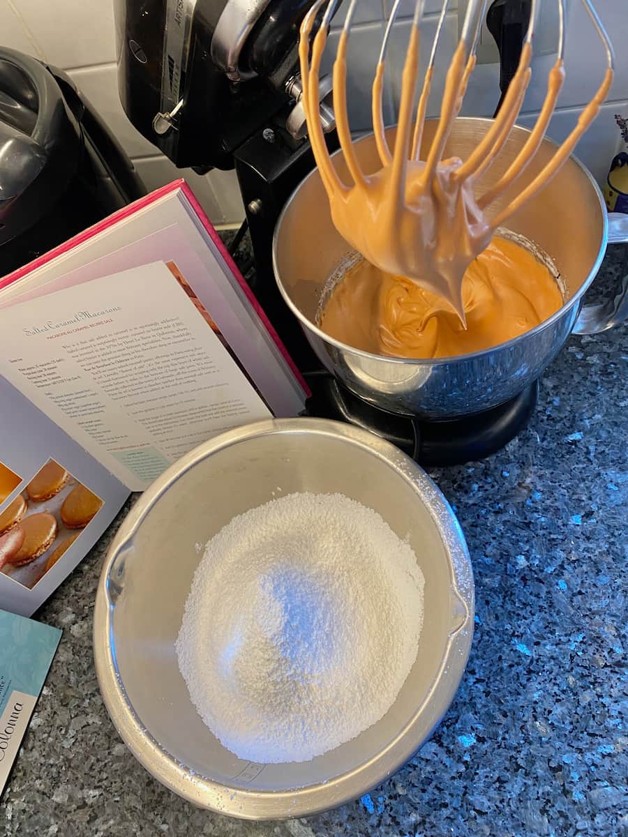 whisking up caramel coloured egg whites next to powdered almonds and sugar to make macarons