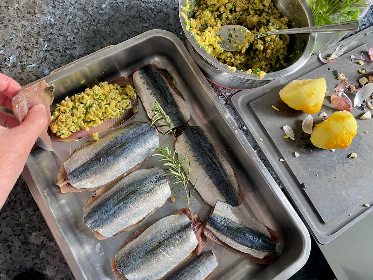 placing herb, lemon and breadcrumb stuffing and placing between two sardine fillets 