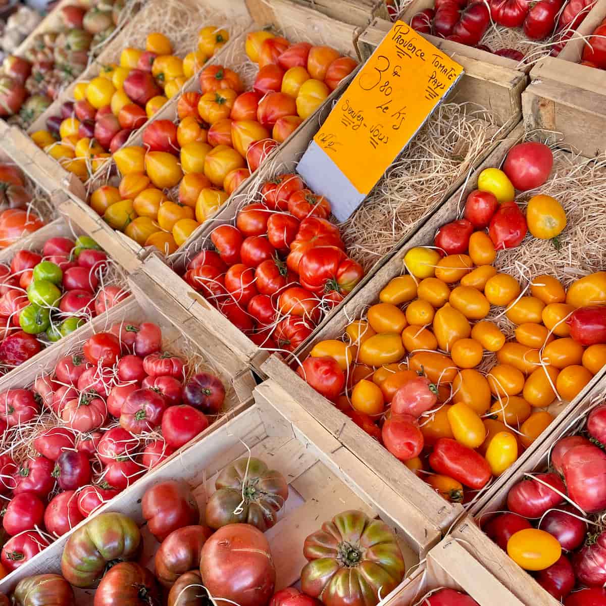 crates of fresh tomatoes in different sizes and colour from red, yellow to green in a Provencal market