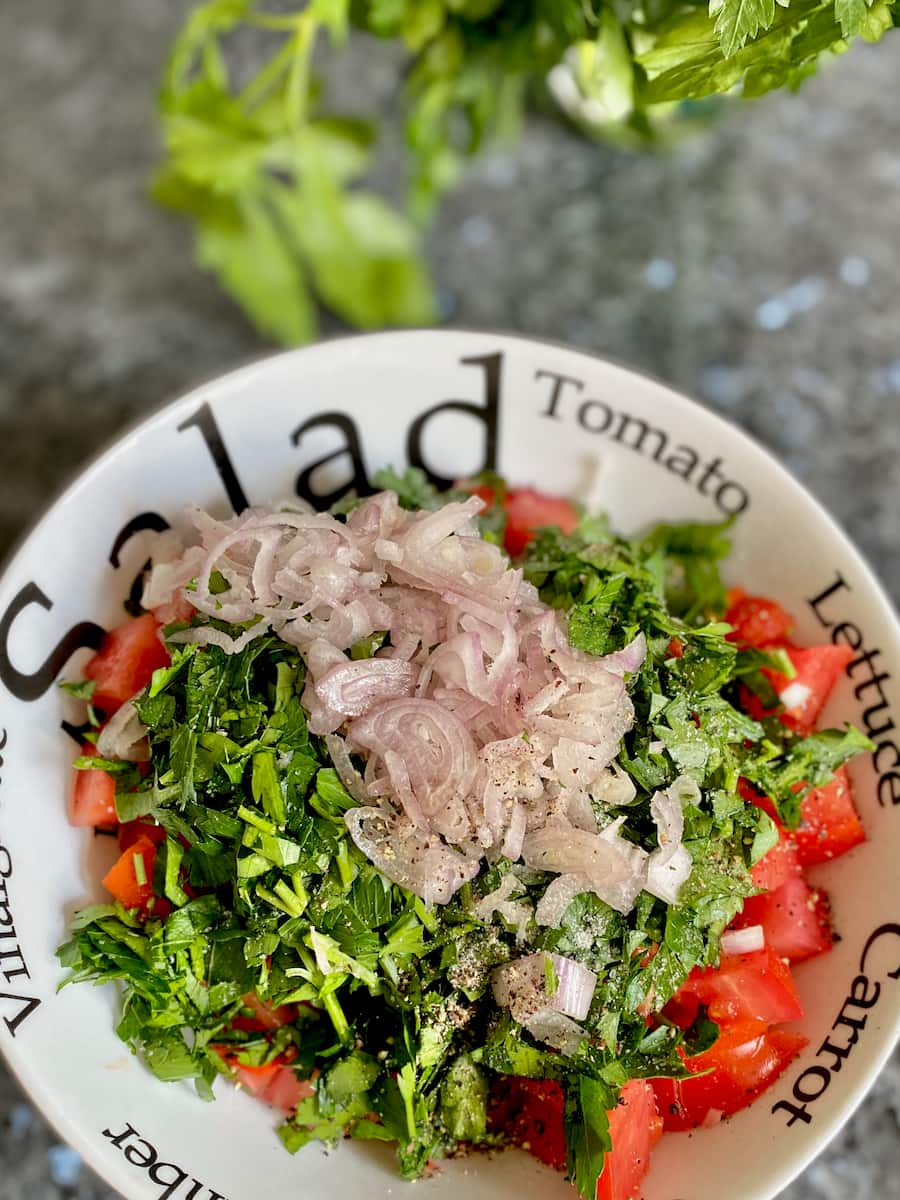 bowl of freshly chopped tomatoes, topped with chopped fresh parsley, shallots and seasoning.