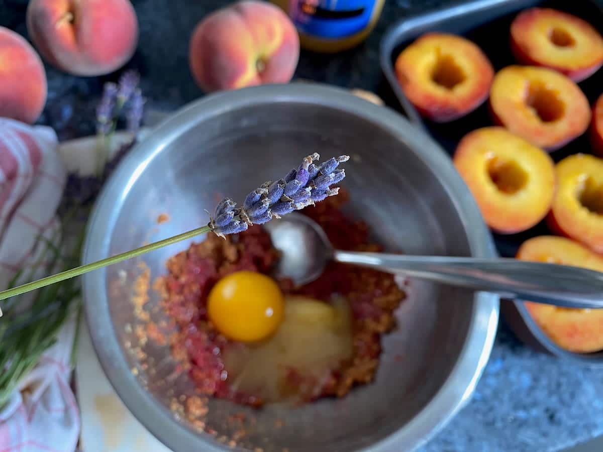 lavender flower about to be added to a mix of honey, egg yolk, crushed raspberries and amaretti to stuff peaches