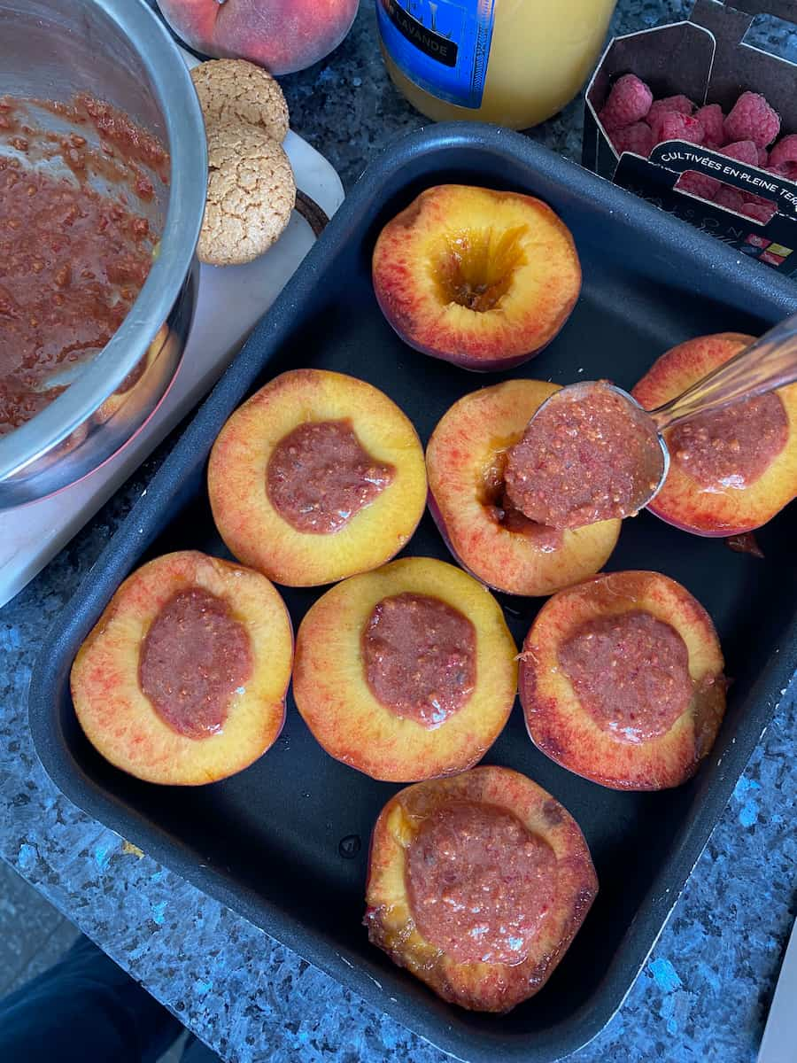 stuffing peaches with an almond and raspberry filling placed face up in a baking tin