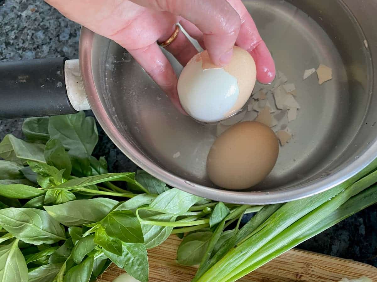 peeling the shell off a hard boiled egg to add to a French salad