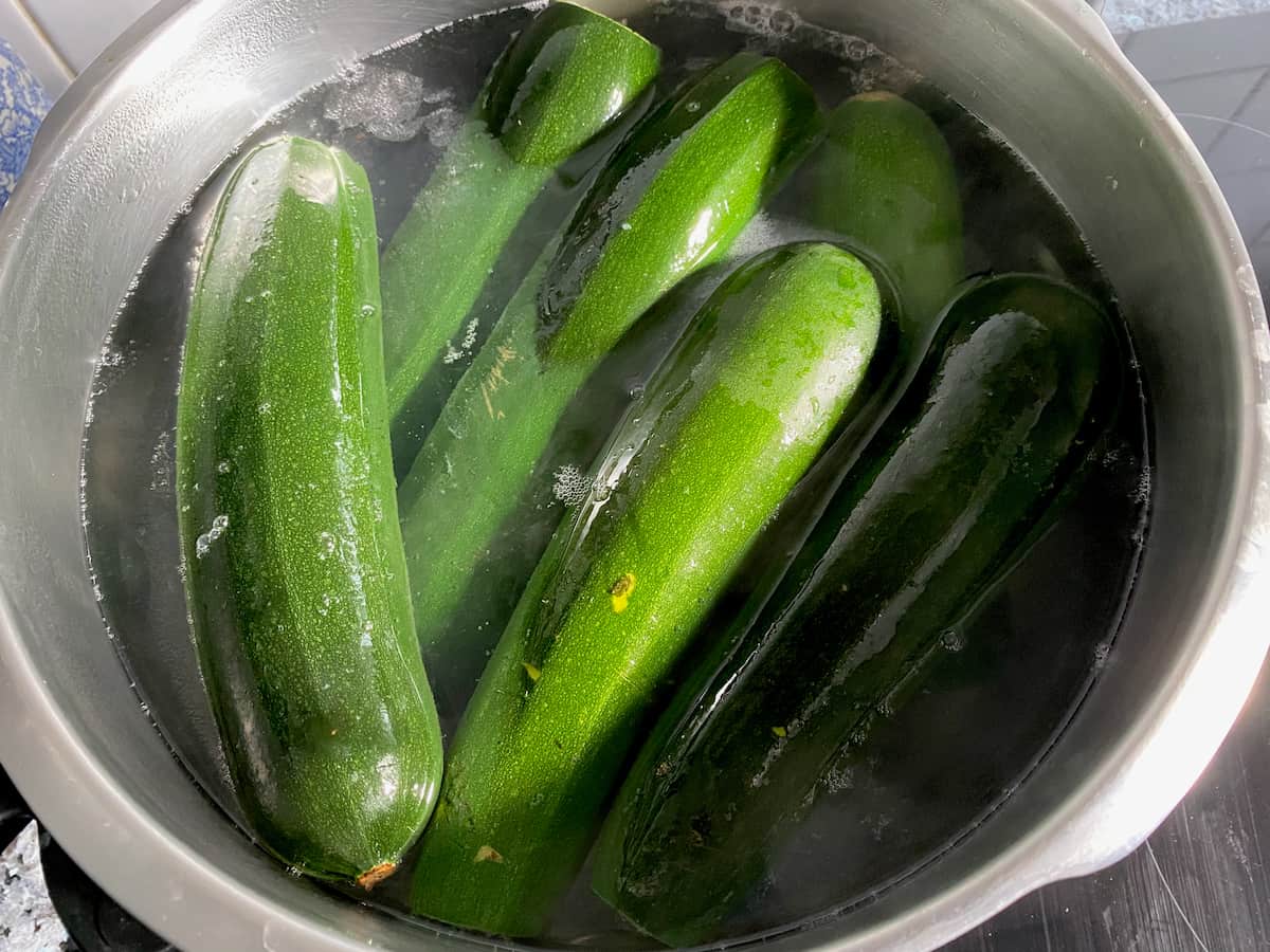 cooking whole zucchini in a large pot of boiling salted water