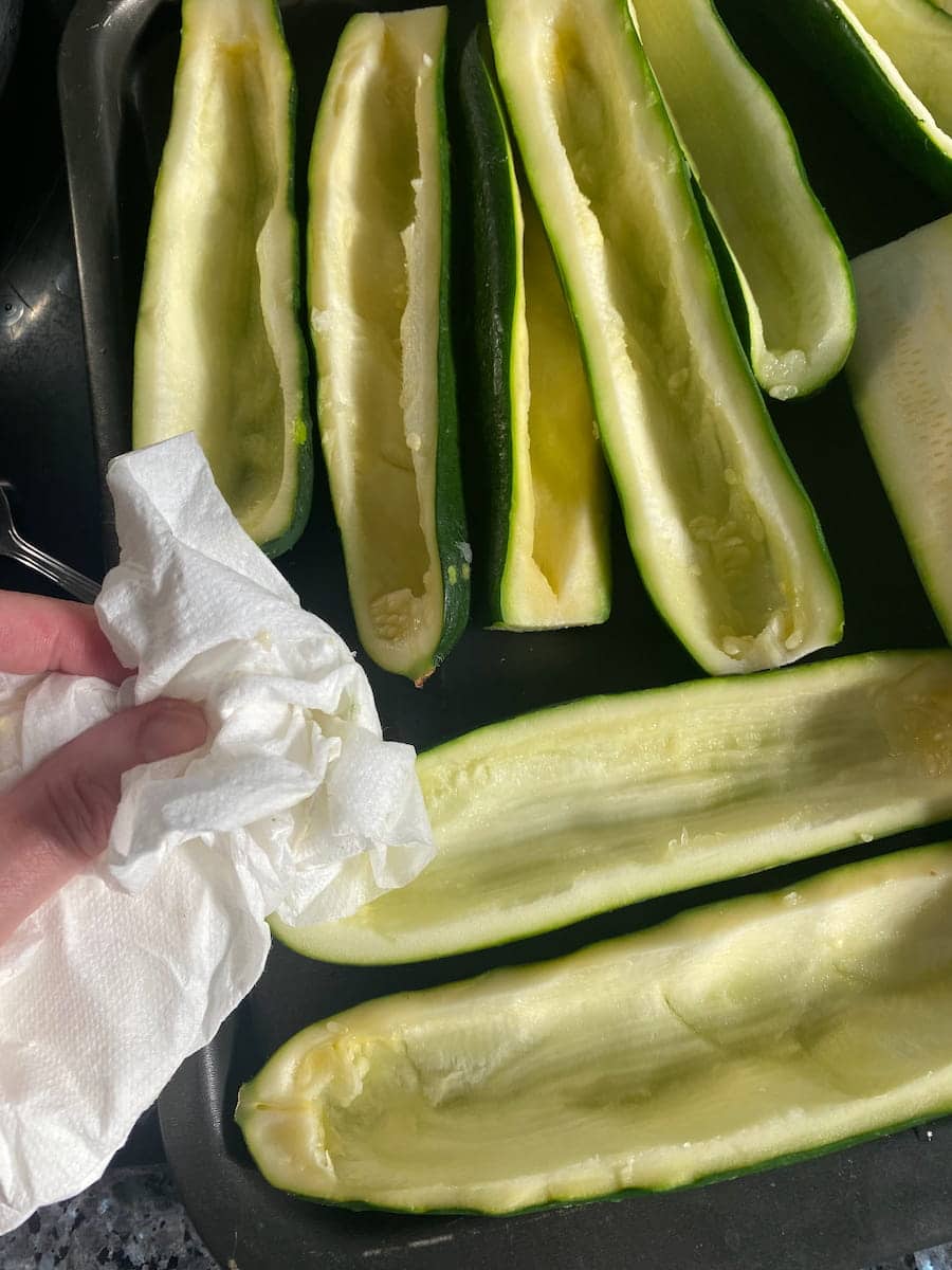 patting dry zucchini boats with kitchen paper