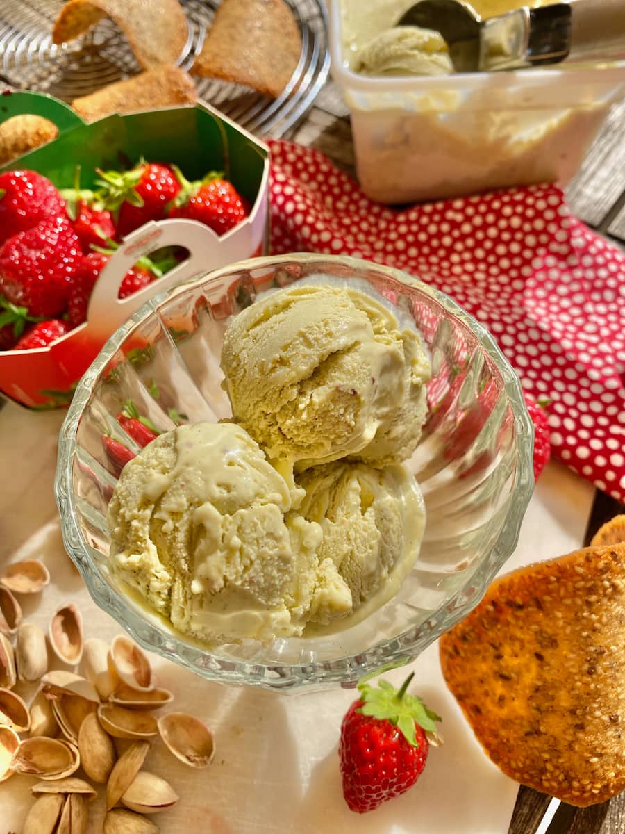 bowl of pistachio ice cream with strawberries and French tuile cookies