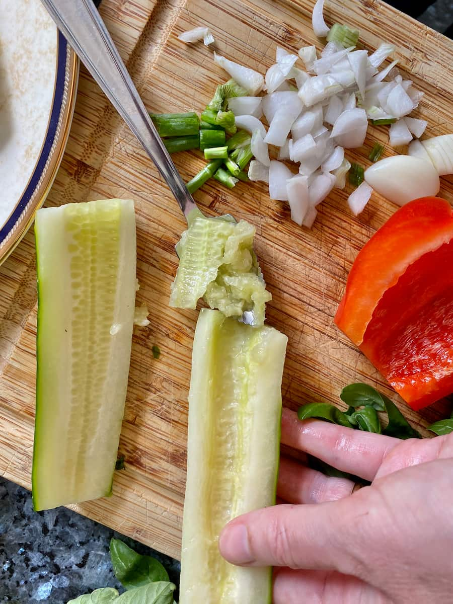 scooping out the middle seeds from half a cucumber for a salad