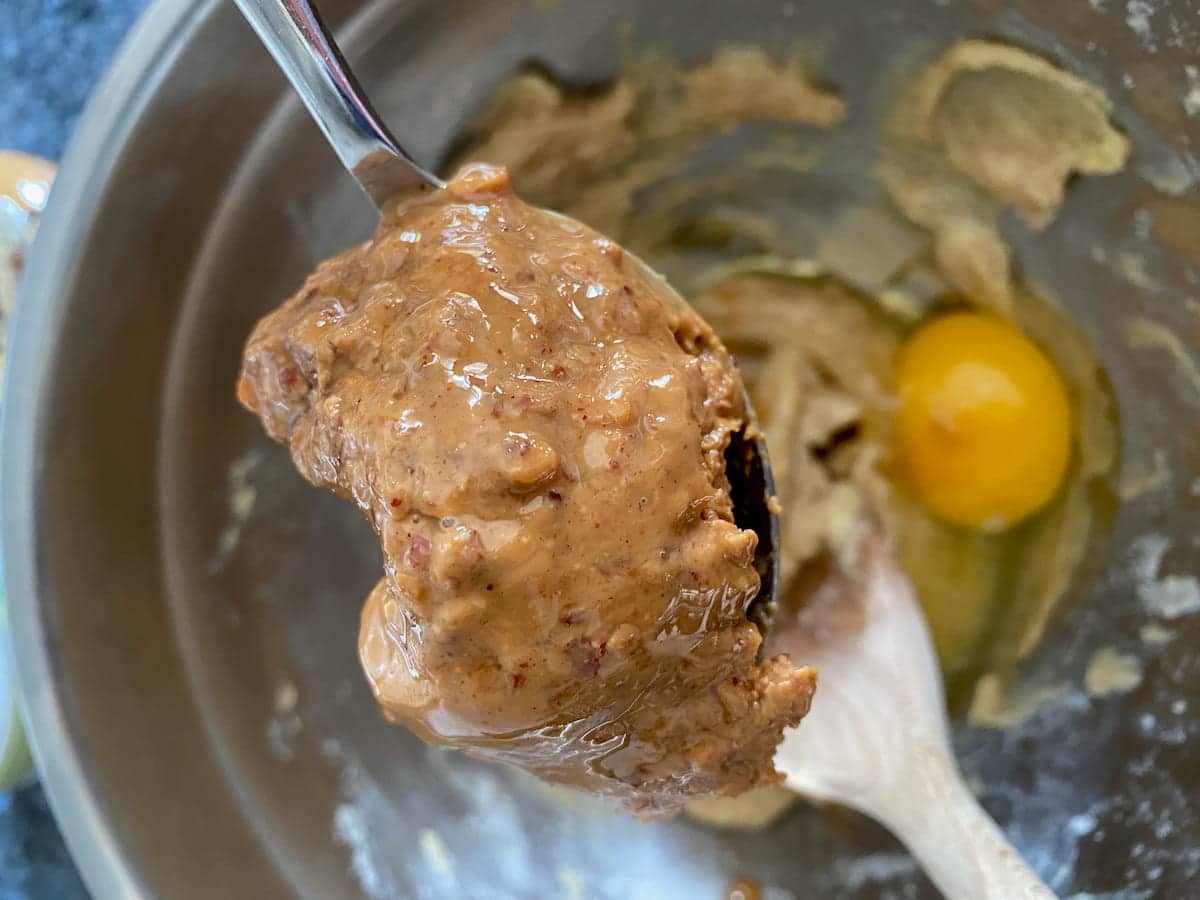 spoonful of natural, healthy peanut butter over a mixing bowl