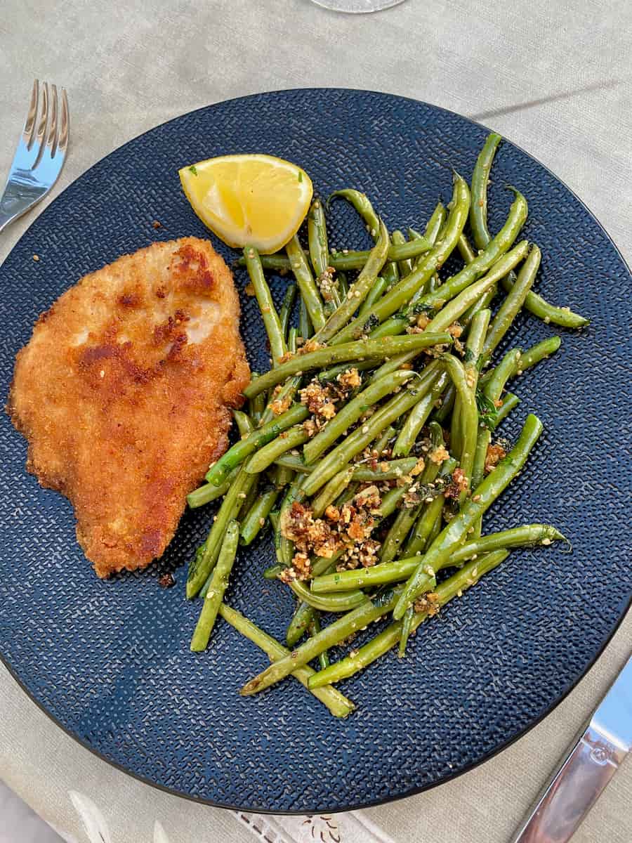 plate of breaded turkey, a wedge of lemon and sauteed green beans