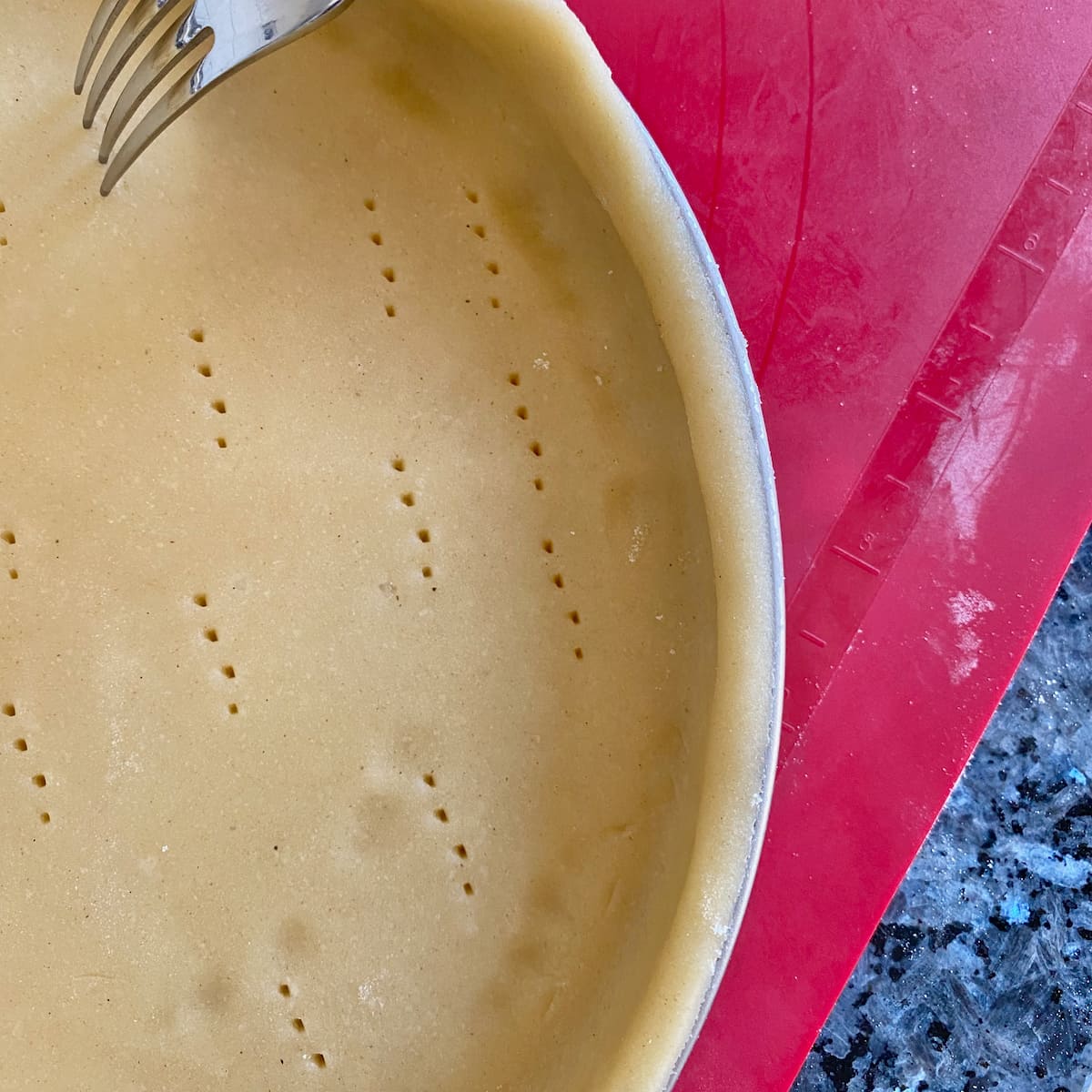 pricking sweet pastry dough in a tart pan 