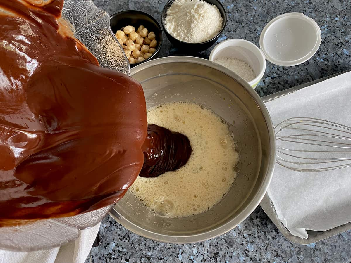 adding melted chocolate and butter to the egg and sugar mix