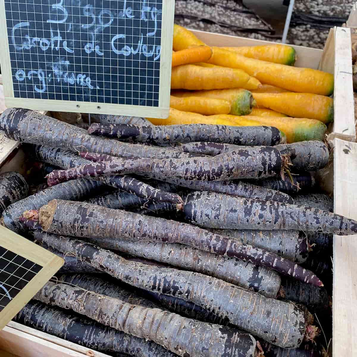 crate of purple and yellow carrots at the French market