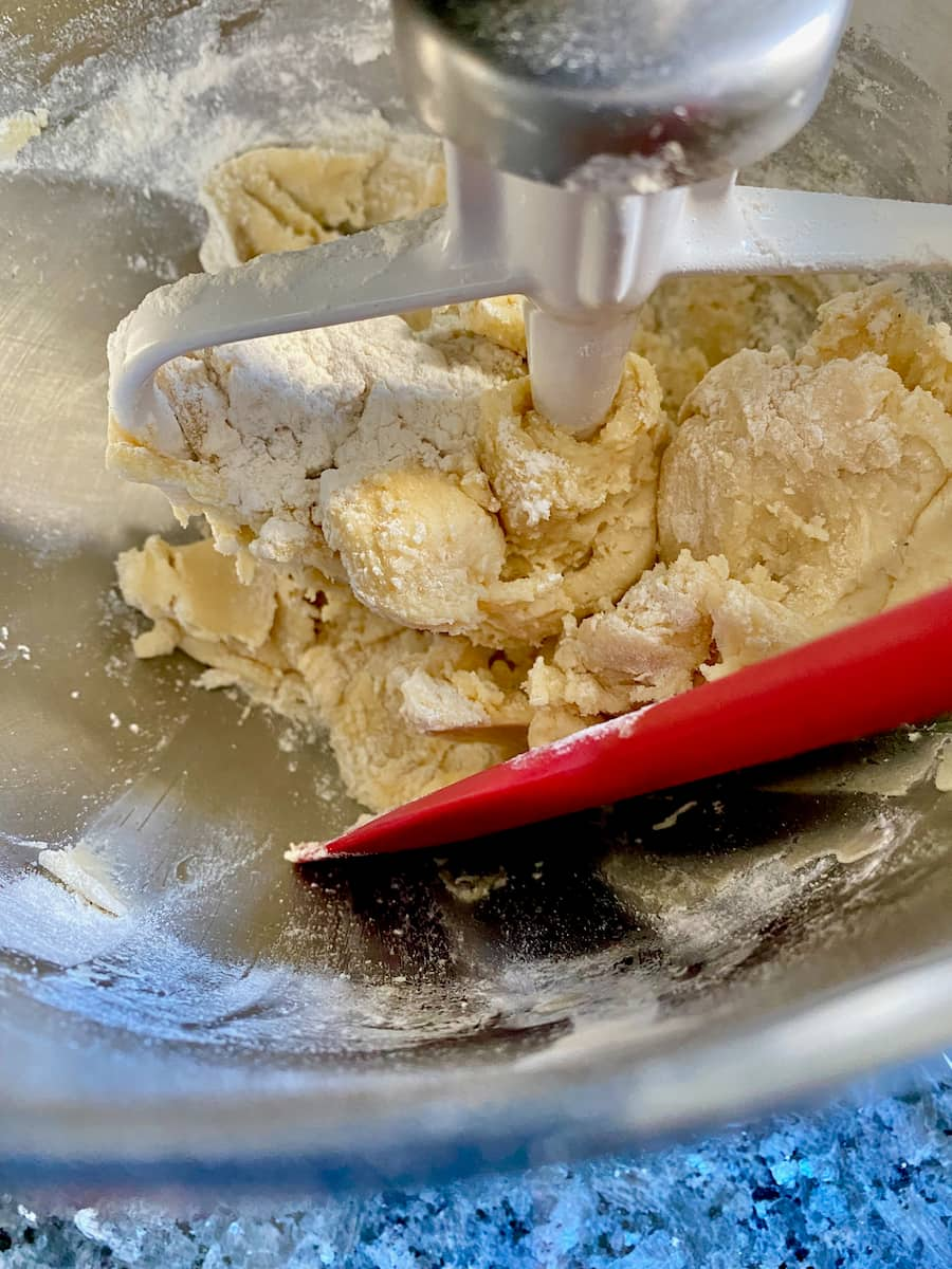 pushing pastry dough with a spatula half way through mixing