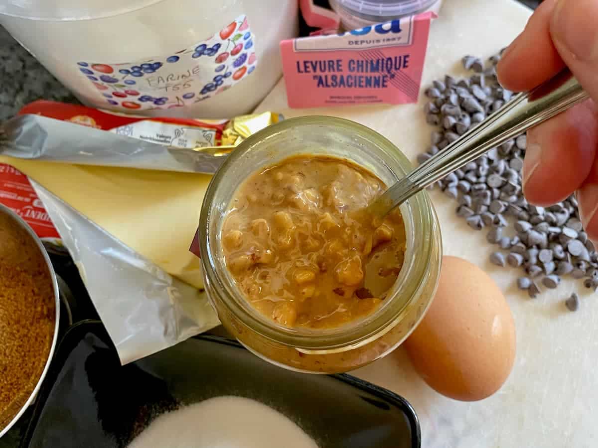 stirring a jar of crunchy peanut butter next to all the cookie's French ingredients