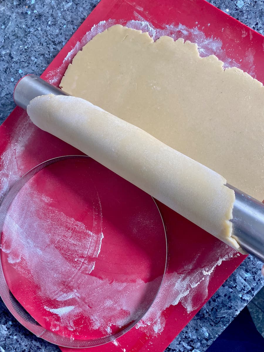 transferring pastry dough using a rolling pin over to the tart tin or ring