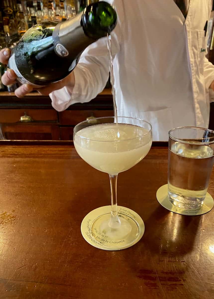 barman in Paris topping up a cocktail with Champagne