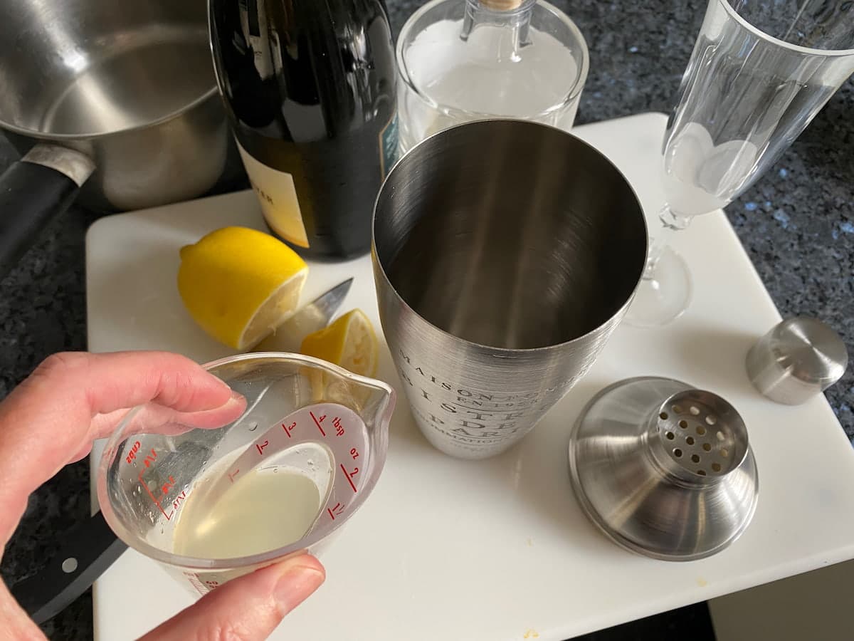 cocktail shaker with French 75 ingredients of freshly squeezed lemon juice, gin, syrup and Champagne