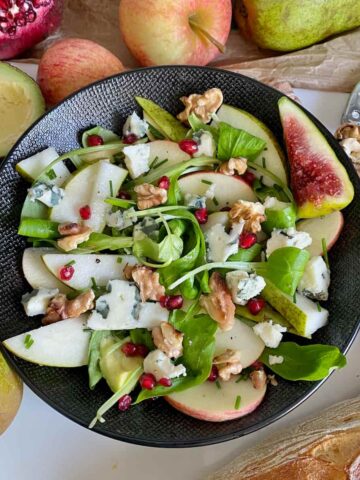 blue cheese crumbled into a green salad with pear, apple and walnuts