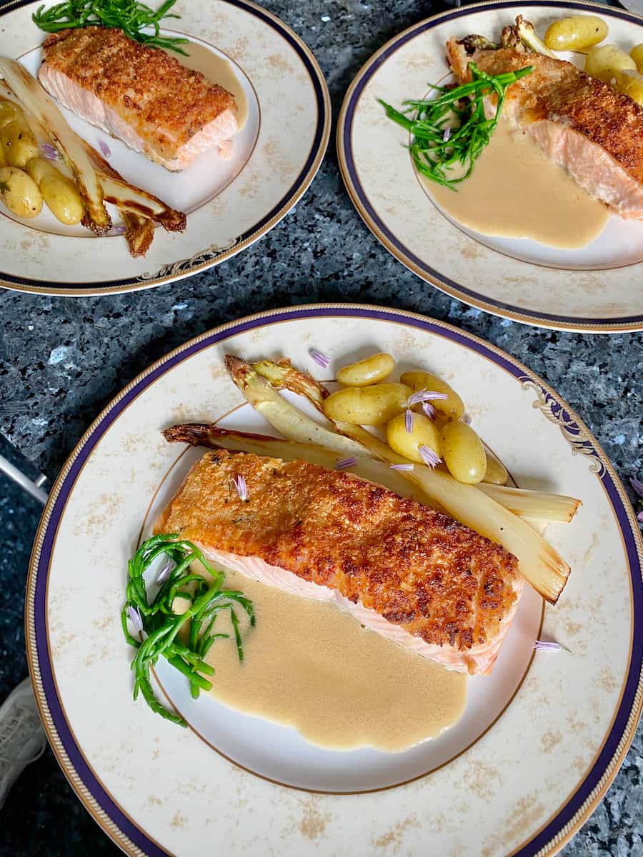 herb crusted salmon fillets with a beurre blanc sauce, potatoes and asparagus