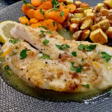 pan-fried John Dory fish filet topped with buttery sauce, parsley and served with carrots and potatoes