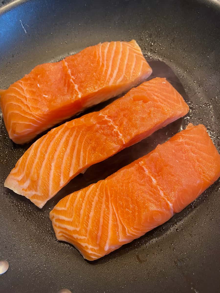 searing salmon fillets in a frying pan