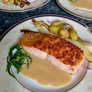 plates of herb crusted salmon with potatoes, asparagus and a butter sauce
