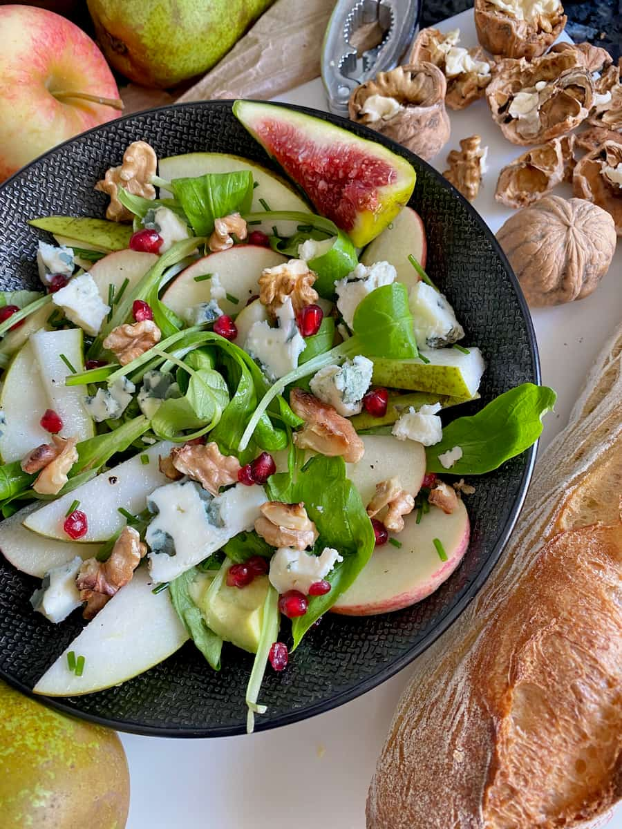 close up of a blue cheese salad with contrasting green, white and red colours and textures with walnuts