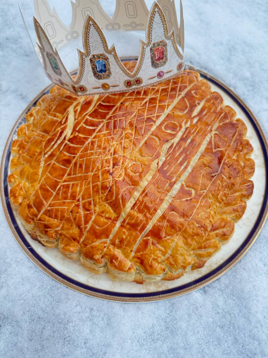 decorated, golden French king cake topped with a paper crown