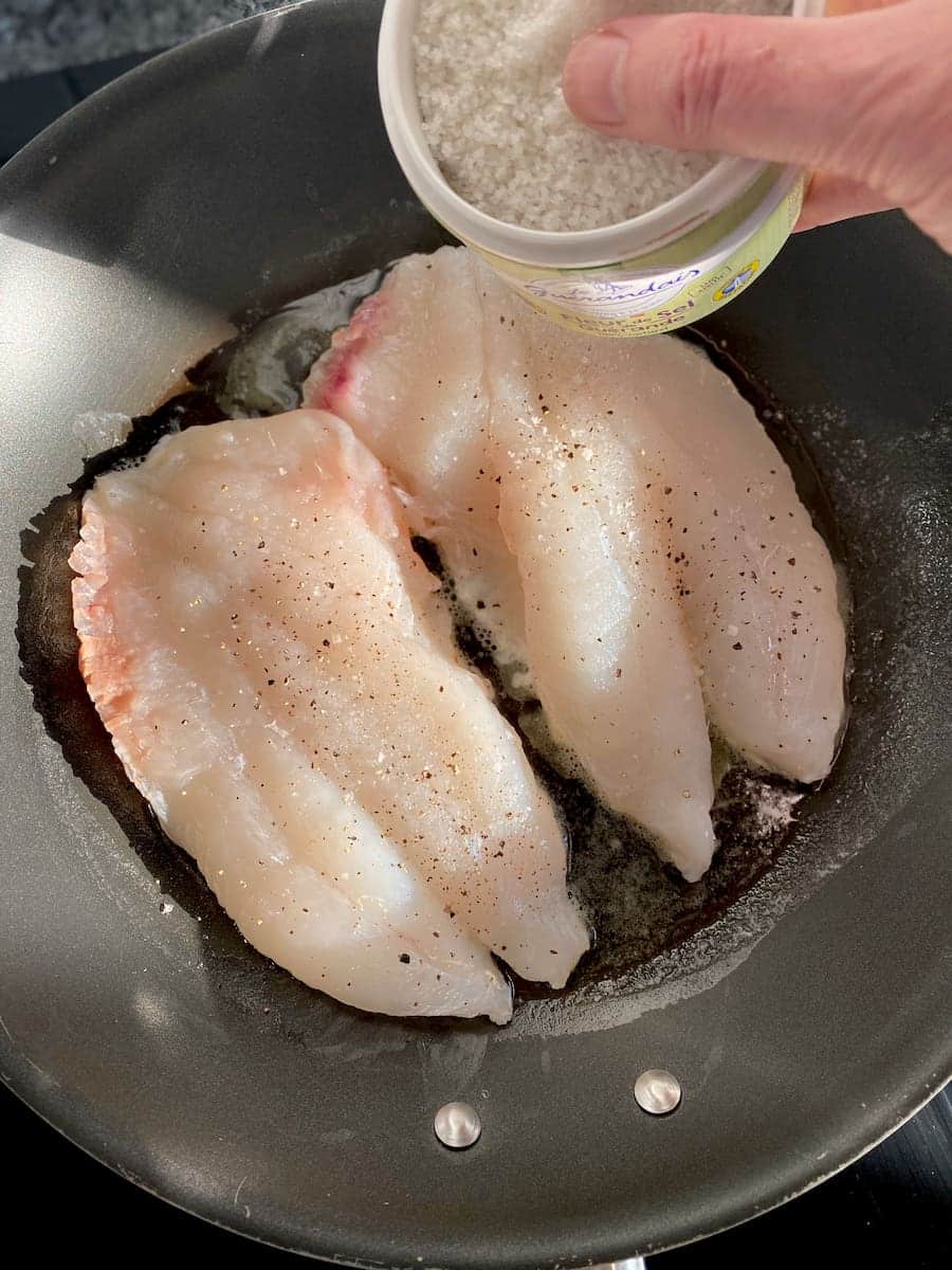 pan-frying John Dory fish fillets, adding salt and pepper