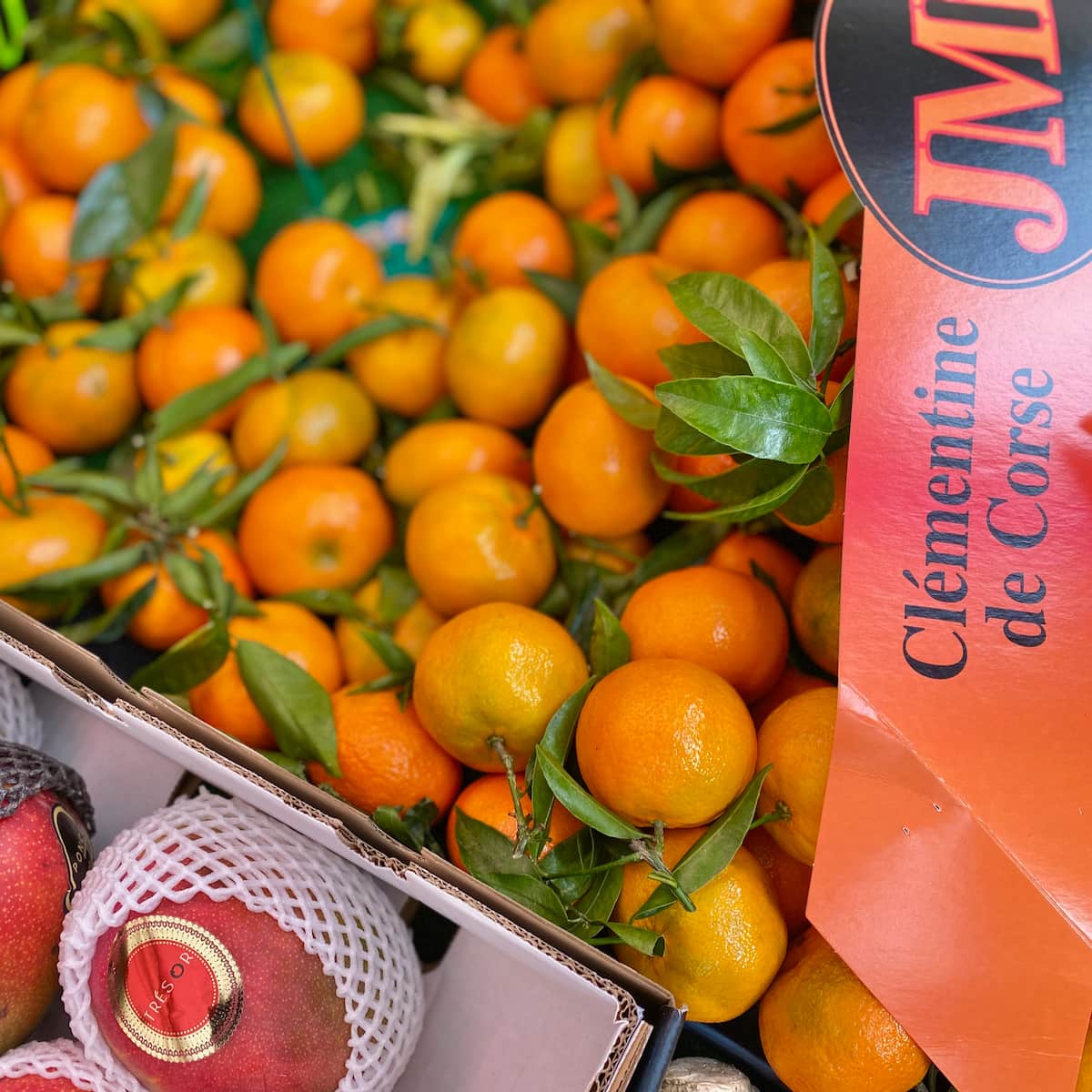 crate of Corsican clementines with tapered leaves in a French market