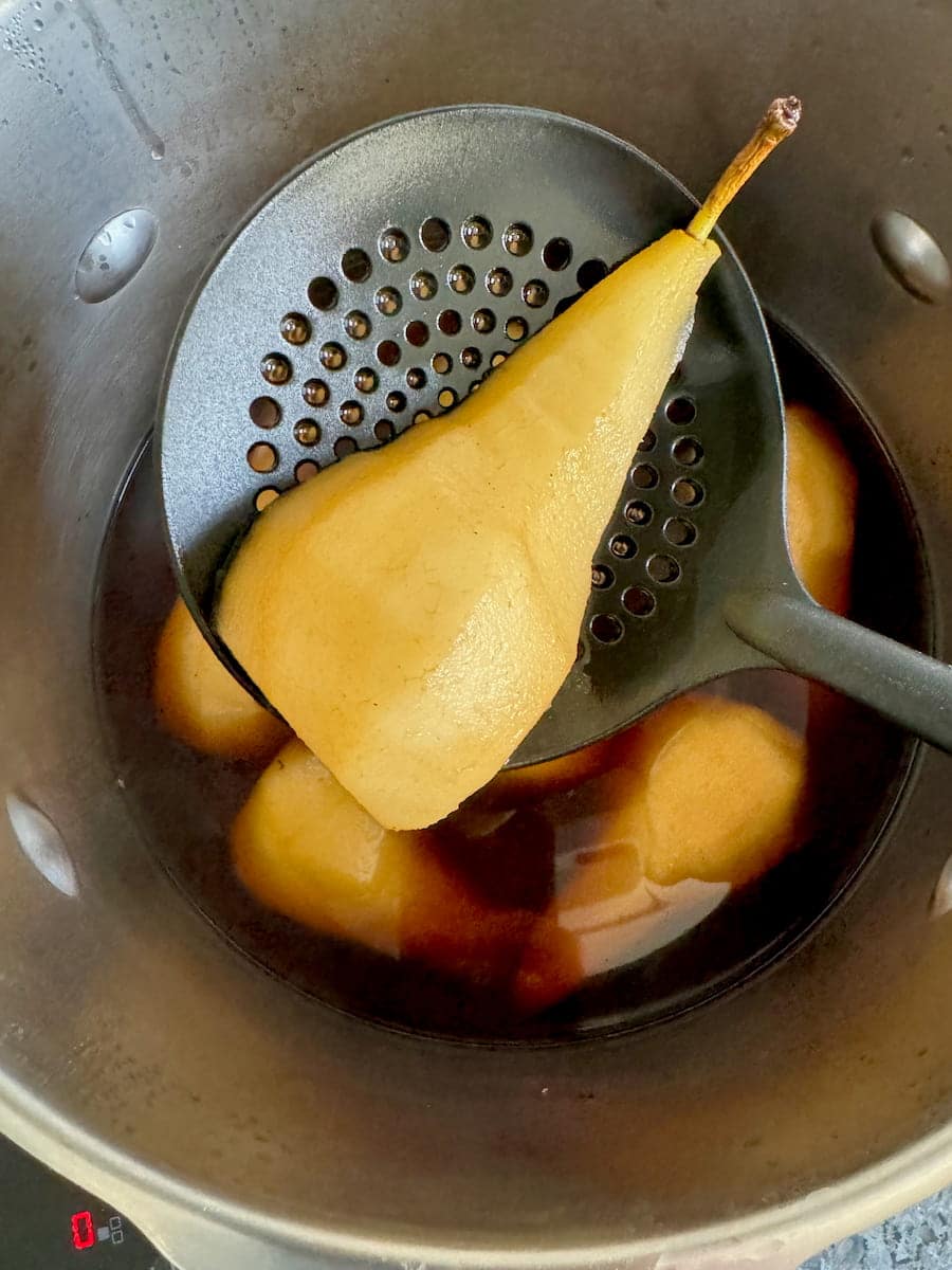 draining a poached pear with slotted spoon