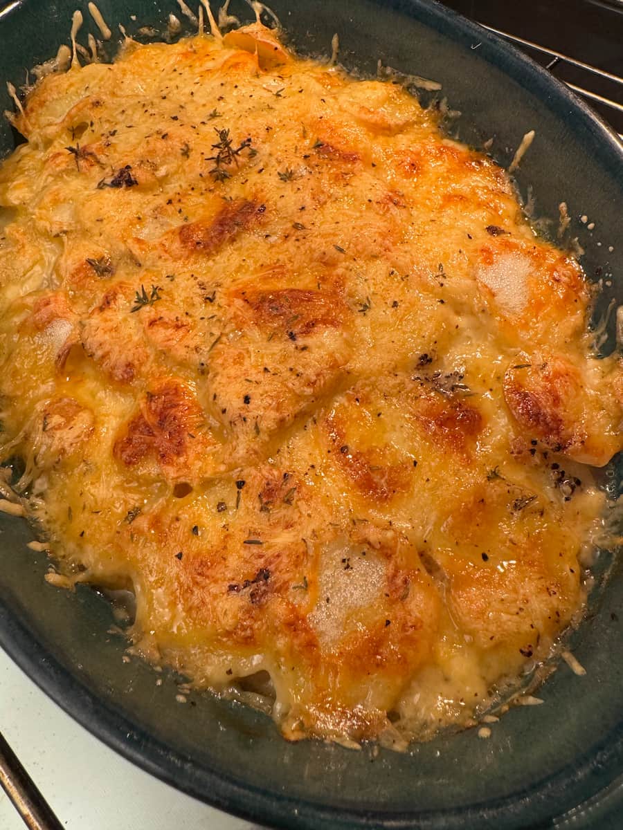 golden cheesy crust with thyme herbs on top of a potato gratin in the oven