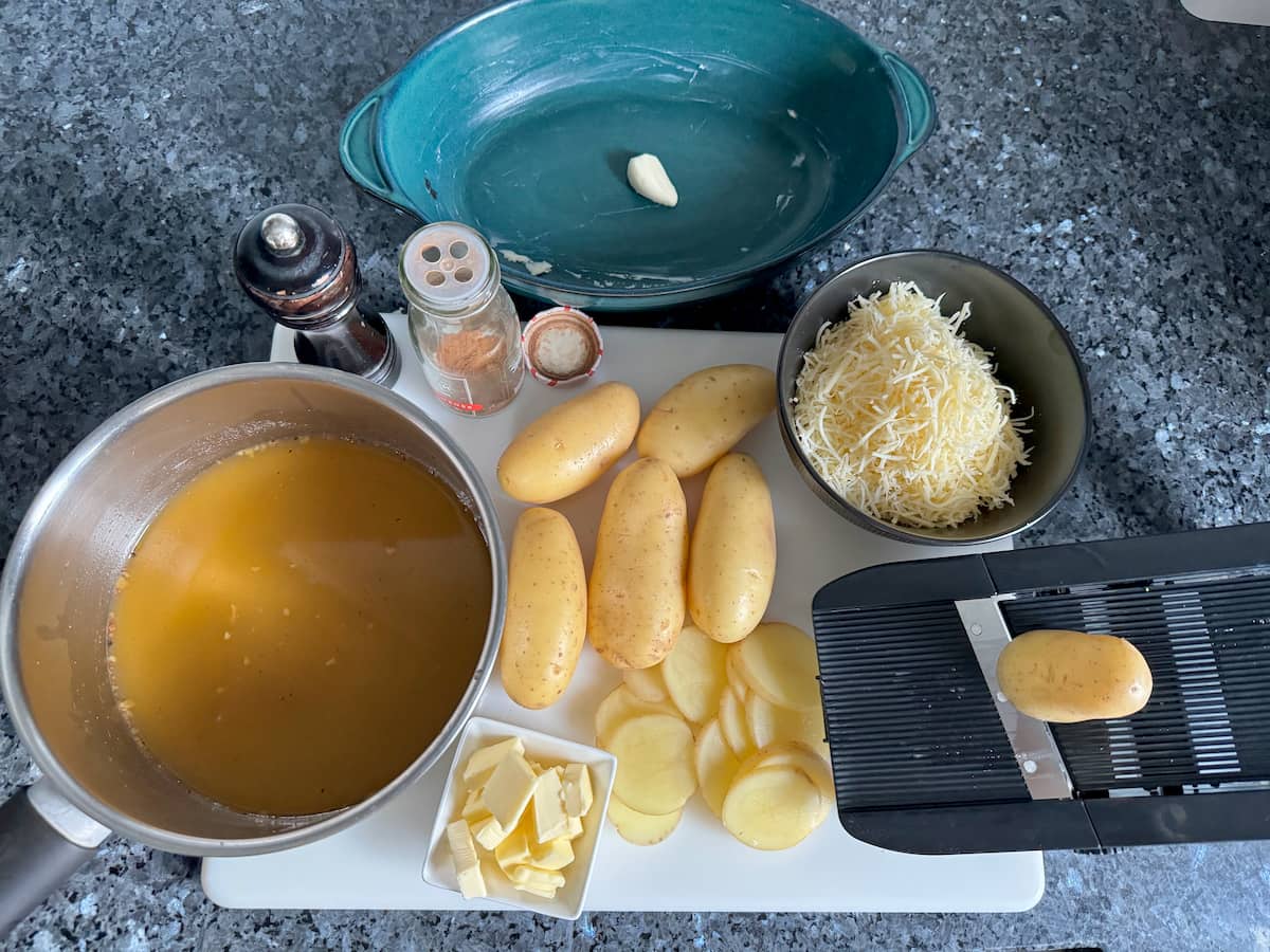 ingredients for a Savoyard potato gratin with chicken stock, potatoes, grated cheese and seasoning