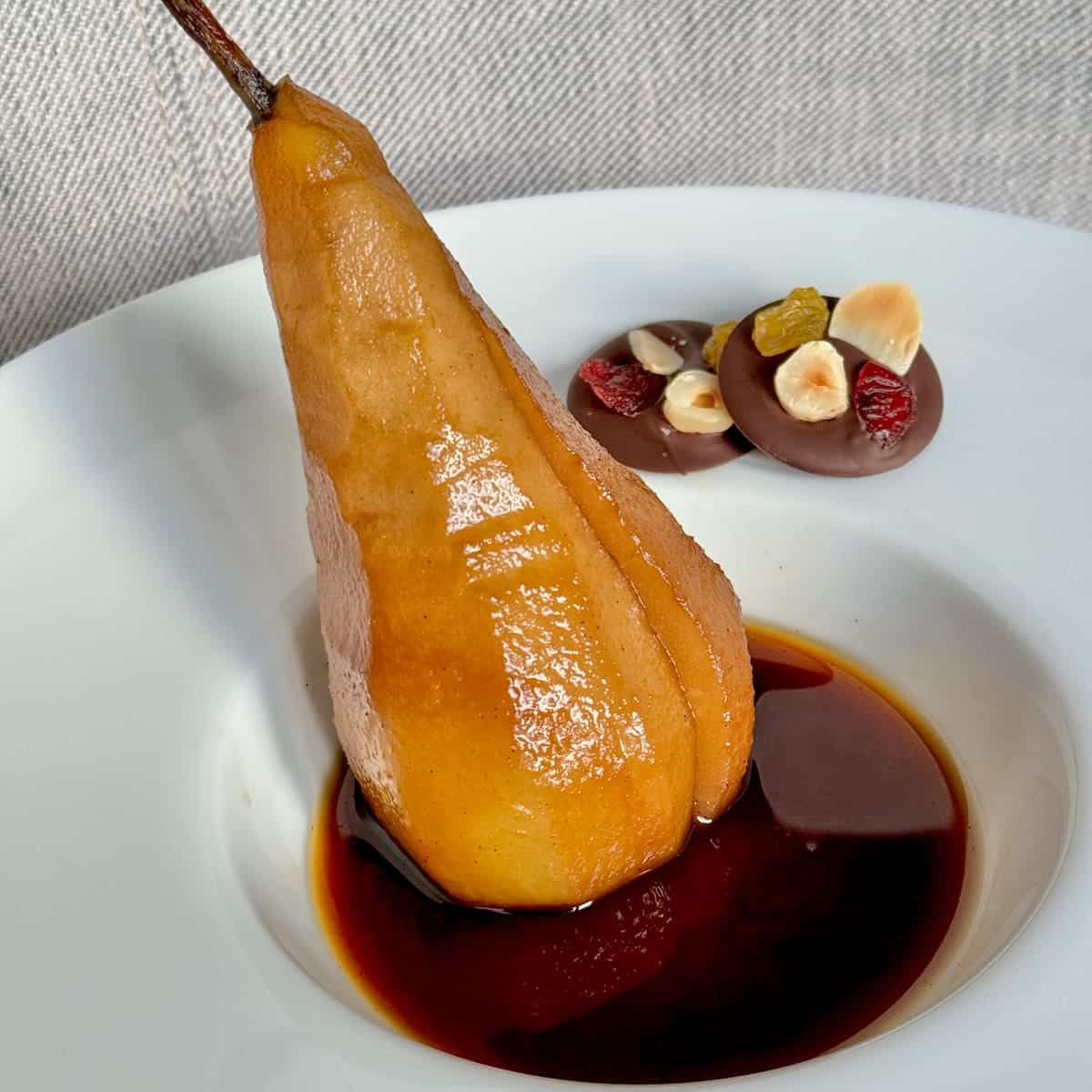 Long poached pear in coffee syrup with mendiant chocolates