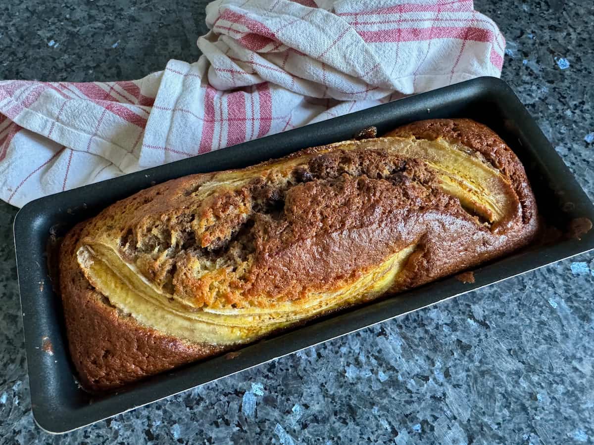 banana bread in a loaf tin topped with sliced banana