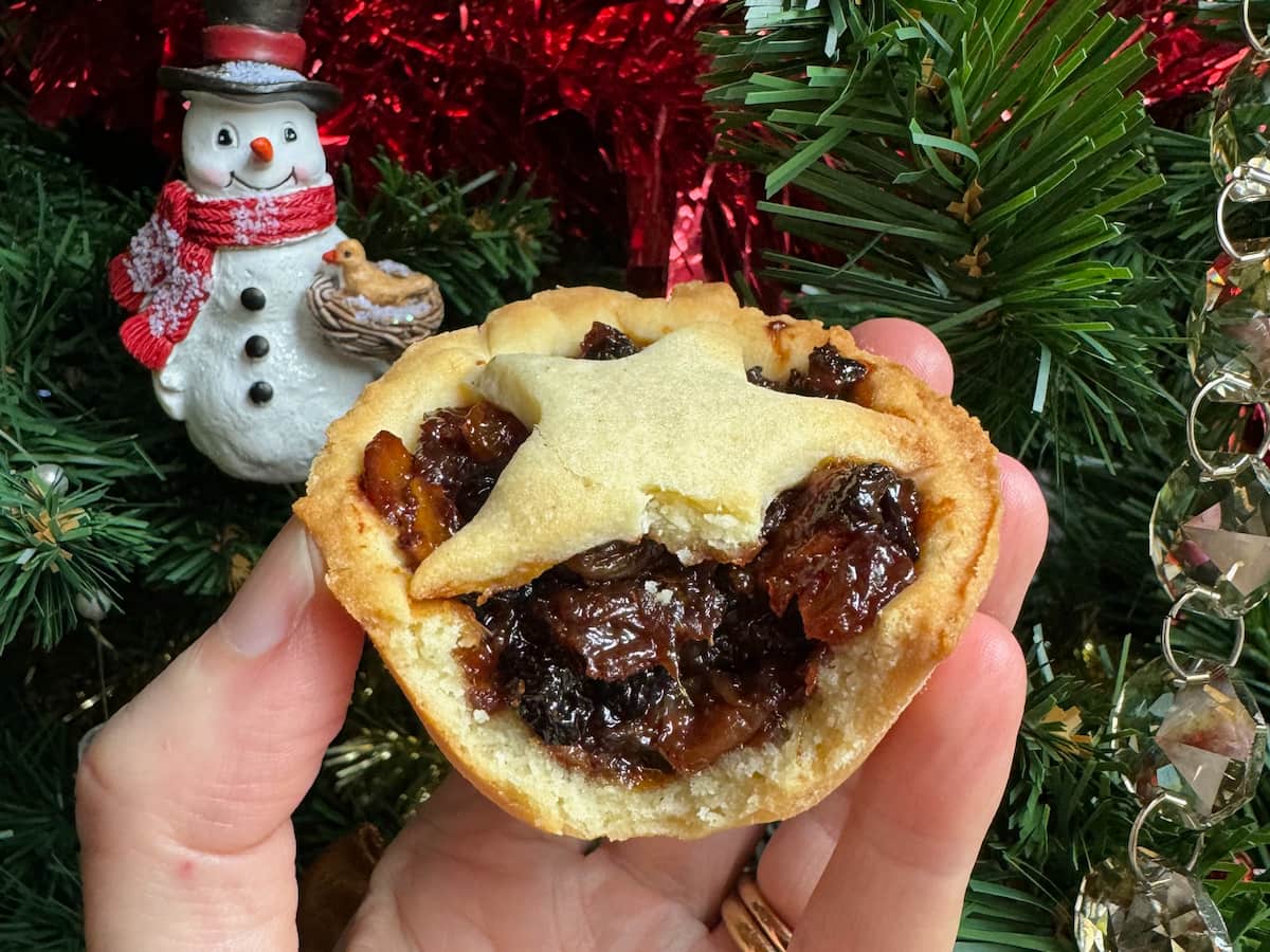 half eaten homemade mince pie, showing the delicious inside with dried fruits and nuts
