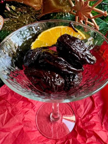 glass dish of prunes soaked in red wine, garnished with orange and spices