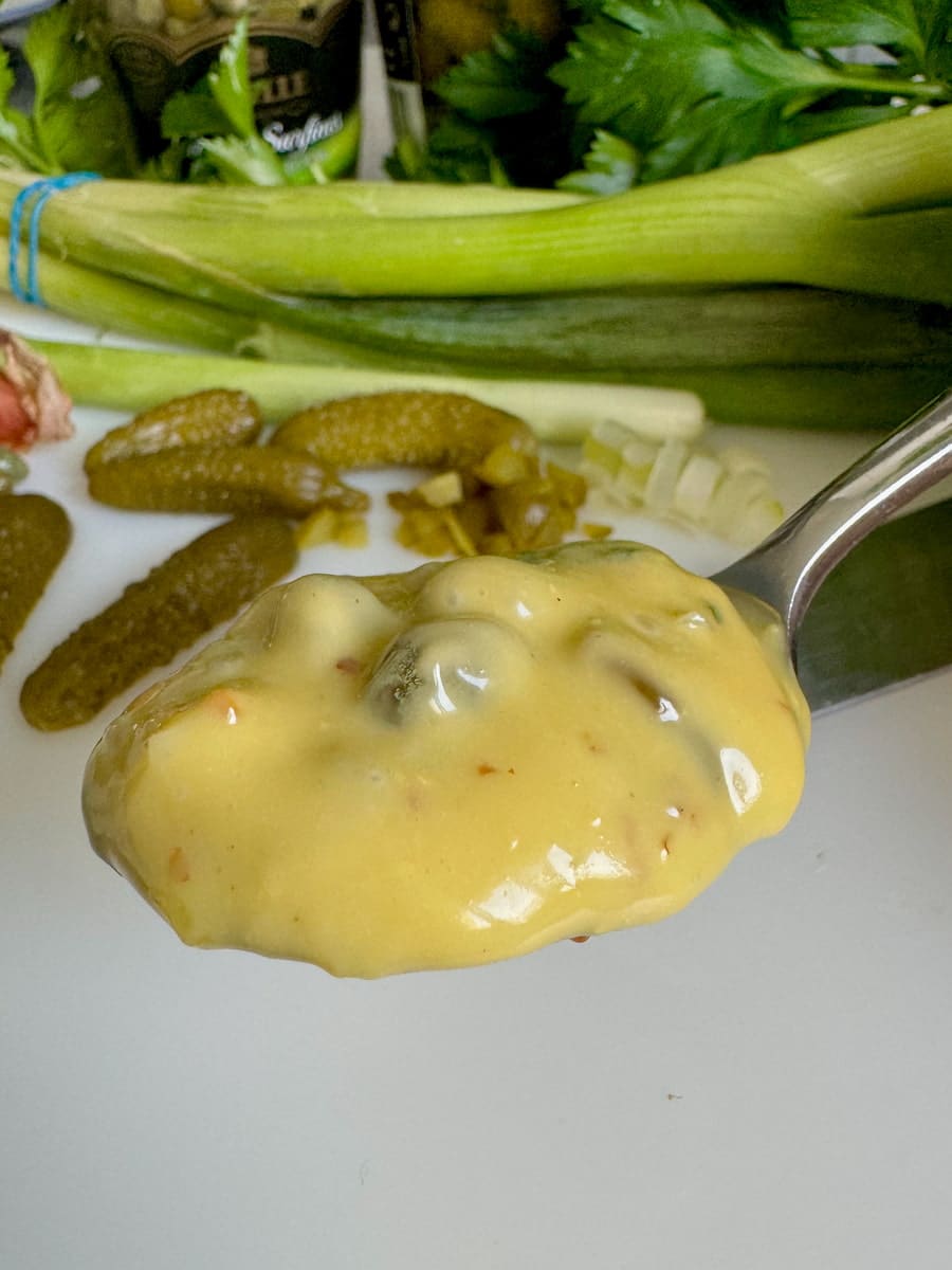 spoonful of thick, shiny Tartar sauce with spring onions, gherkins and capers