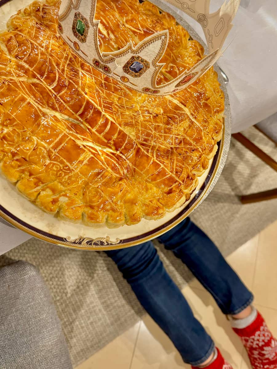 large golden puff pastry cake ready to be served with legs showing of someone under the table