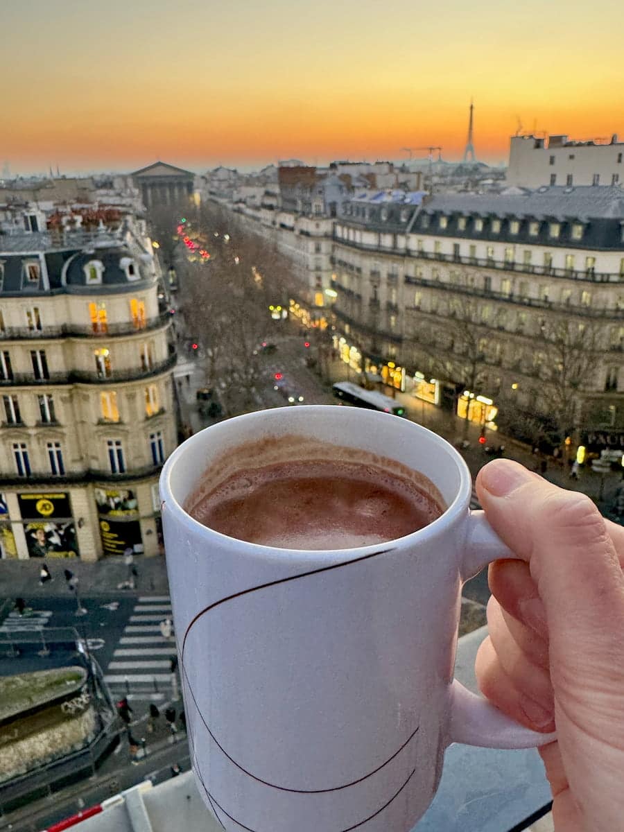 mug of hot chocolate at sunset with a view of the Paris skyline