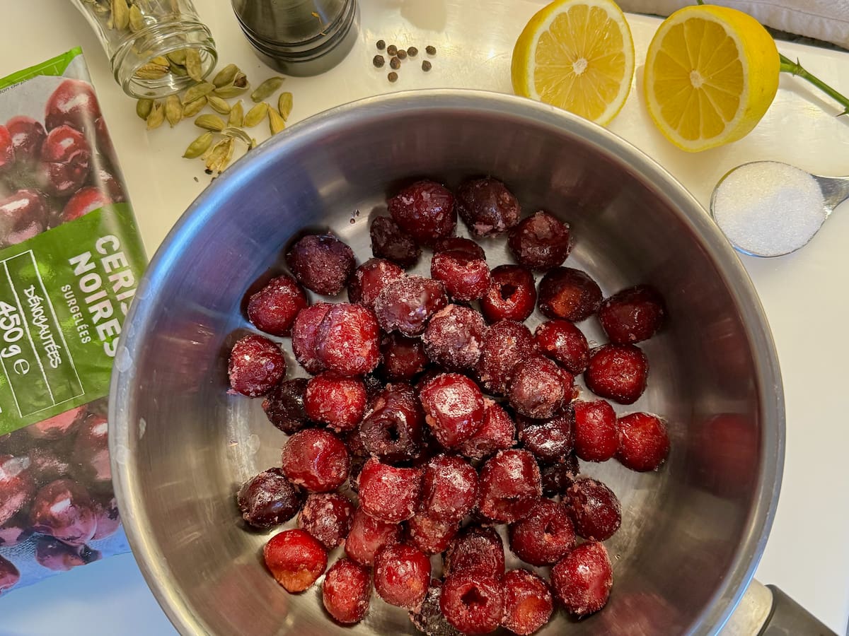 pan of frozen cherries, cardamom spices, lemon, pepper and sugar