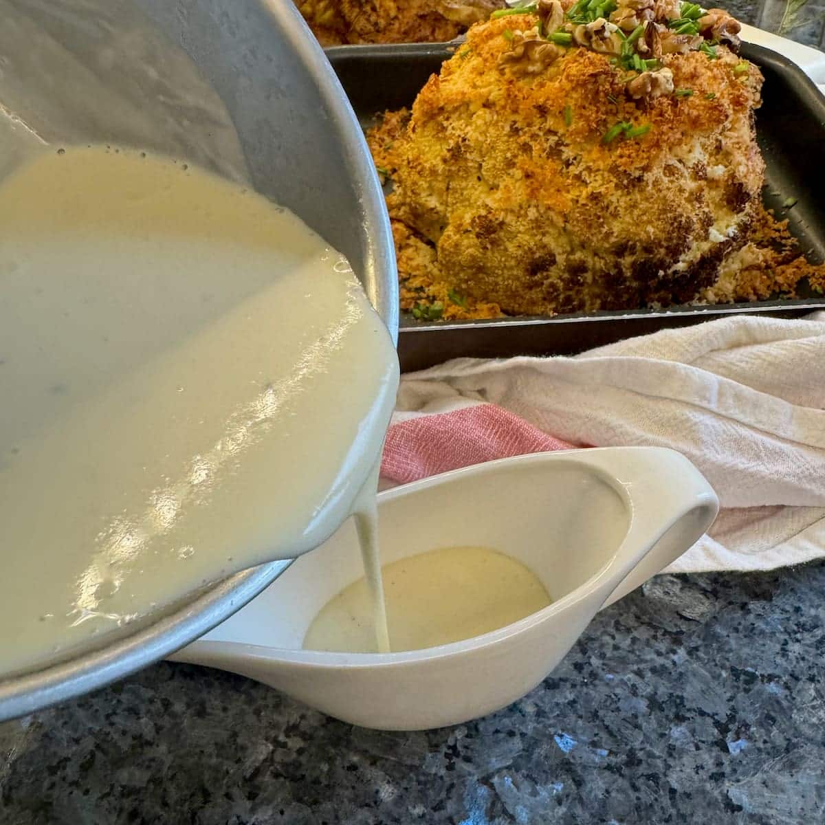 pouring béchamel into a sauce boat