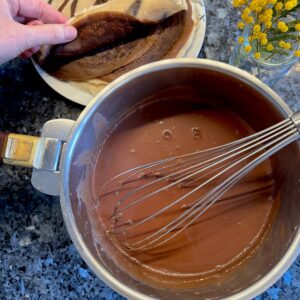 whisking dark chocolate sauce in a pan with milk and cream and real chocolate (not powder)