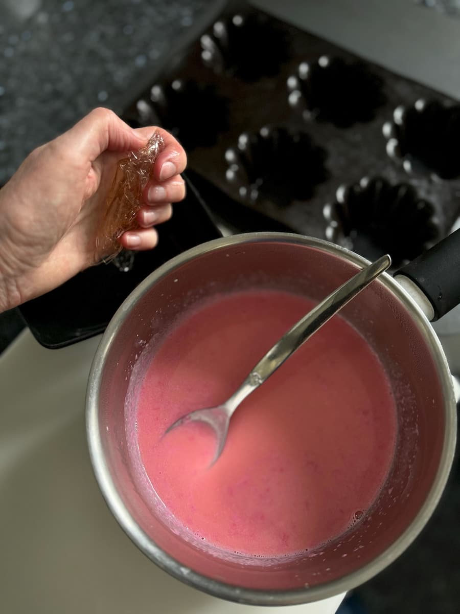 squeezing soaked gelatine into cooked cream with rose