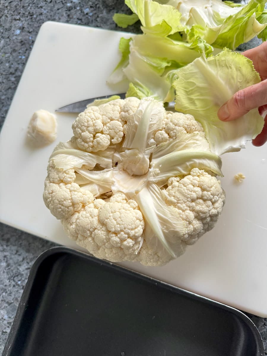 cutting off outer leaves of a cauliflower