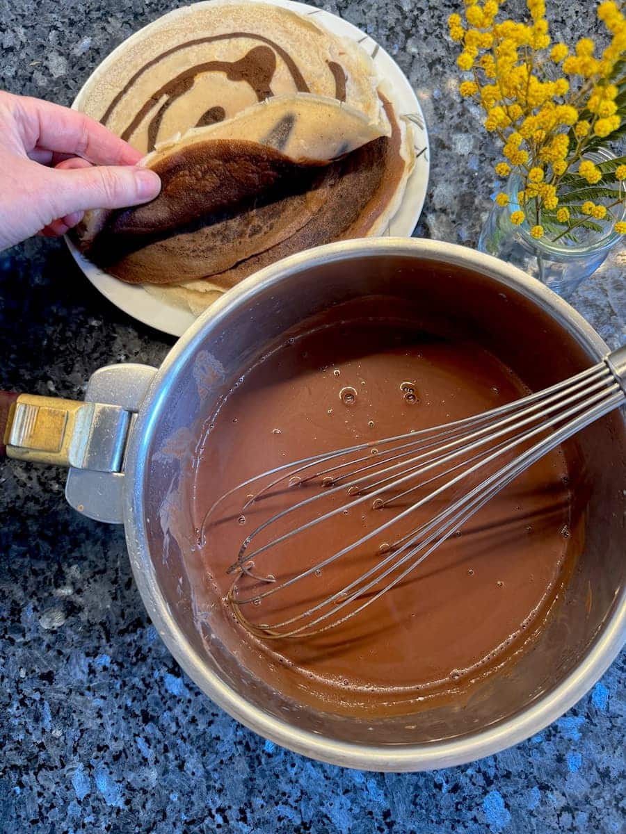 whisking dark chocolate into milk and cream to make a sauce