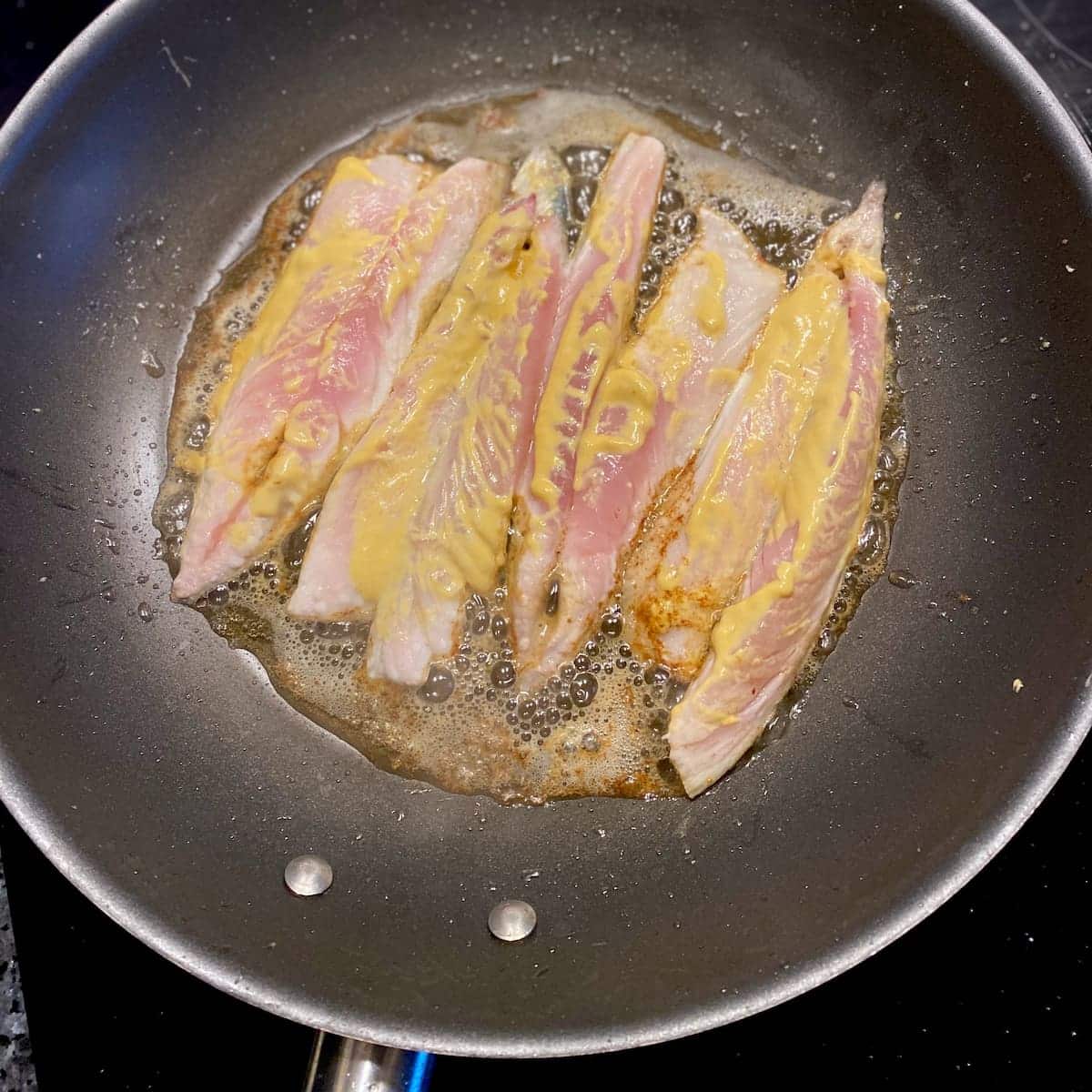 frying mackerel fillets in a pan with mustard, a little olive oil and butter